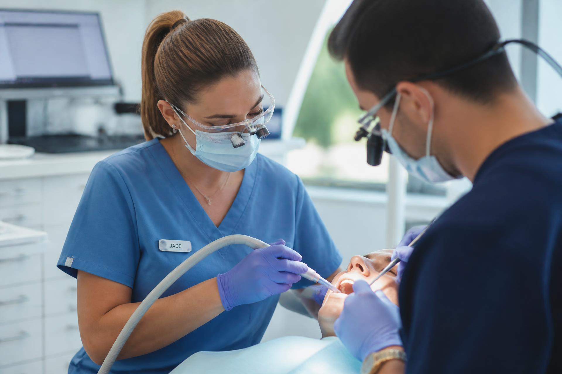 Asistente dental ayudando a un odontólogo durante un procedimiento en un consultorio moderno